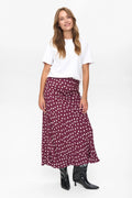 Woman wearing a white top and burgundy polka dot skirt on a white background
