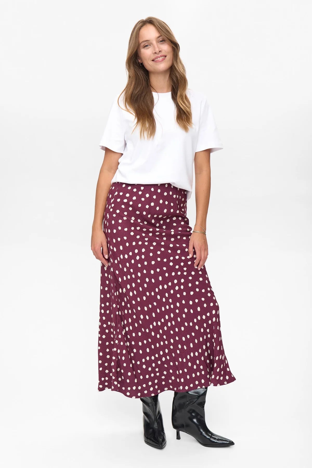 Woman wearing a white top and burgundy polka dot skirt on a white background