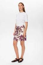 Woman wearing a white top and floral skirt on a white background