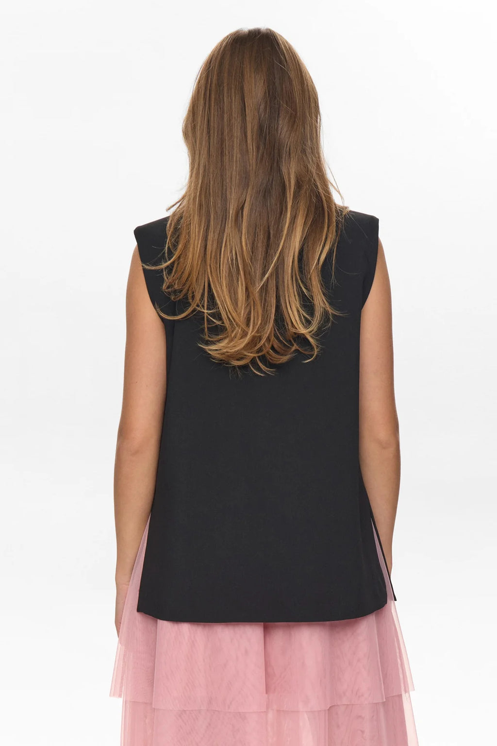 Woman wearing a black top with pink layered skirt on a white background