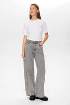 Woman wearing a white t-shirt and gray wide-leg jeans on a white background