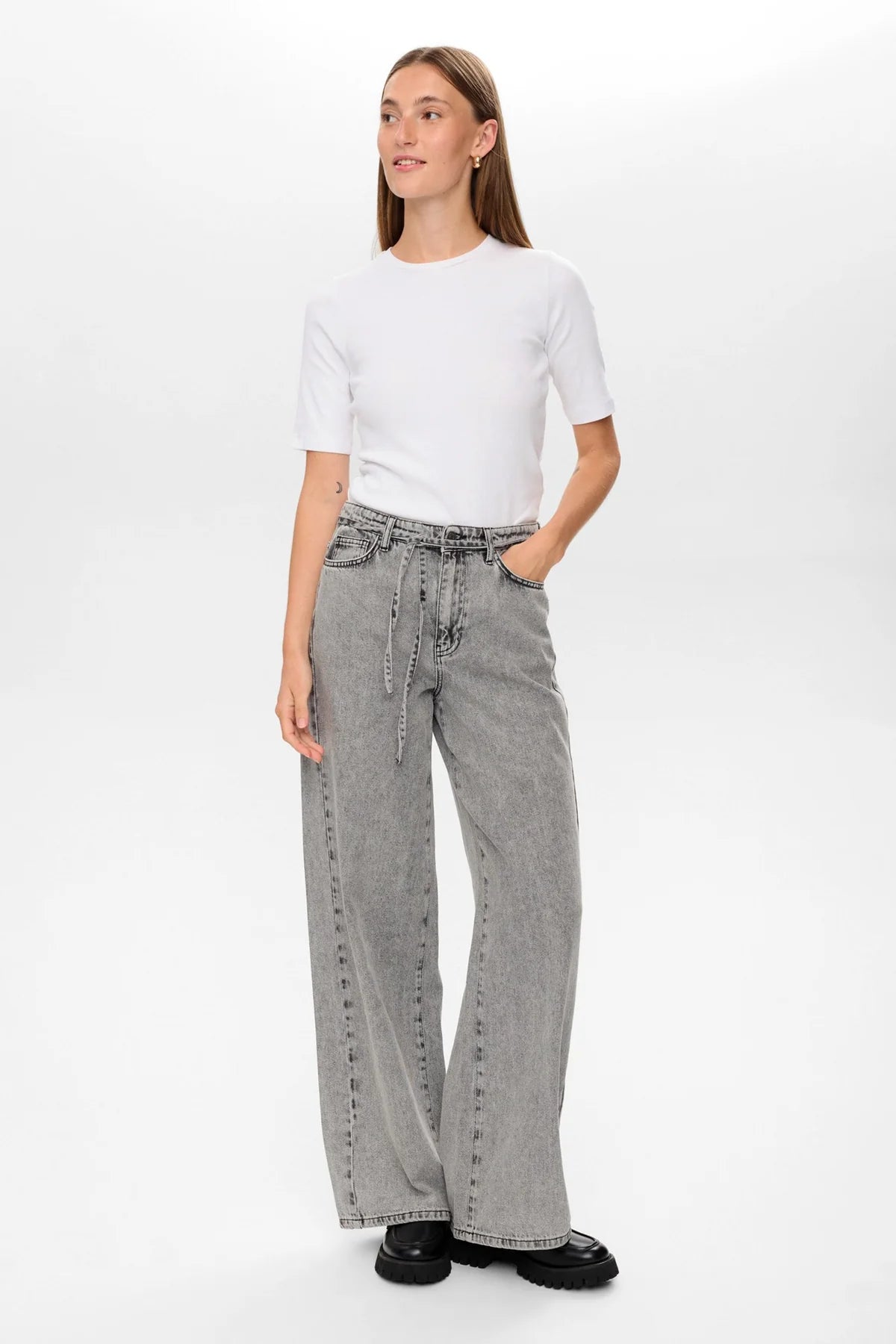 Woman wearing a white t-shirt and gray wide-leg jeans on a white background