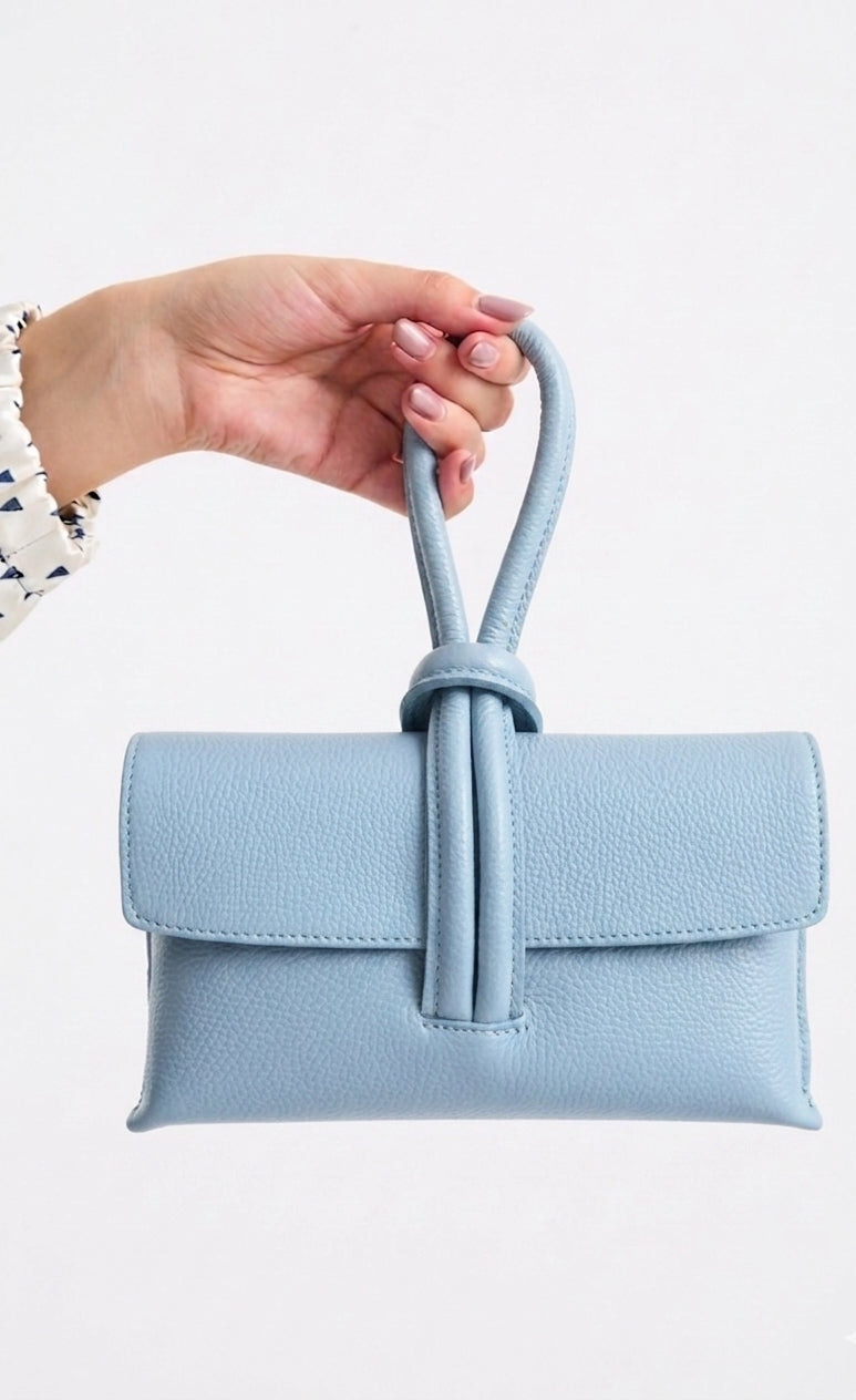 Light blue handbag with a handle held by a hand on a white background