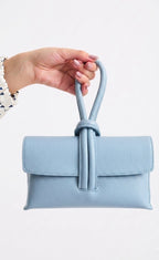 Light blue handbag with a handle held by a hand on a white background