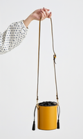 Yellow bucket bag with a strap held by a hand against a white background