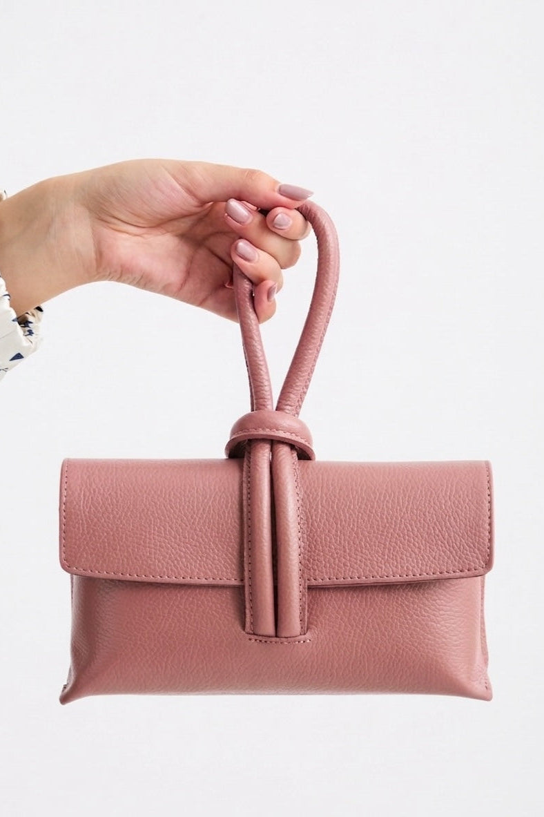 Pink handbag held by a hand on a white background