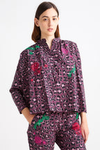 Woman wearing a purple patterned outfit with floral embellishments on a white background
