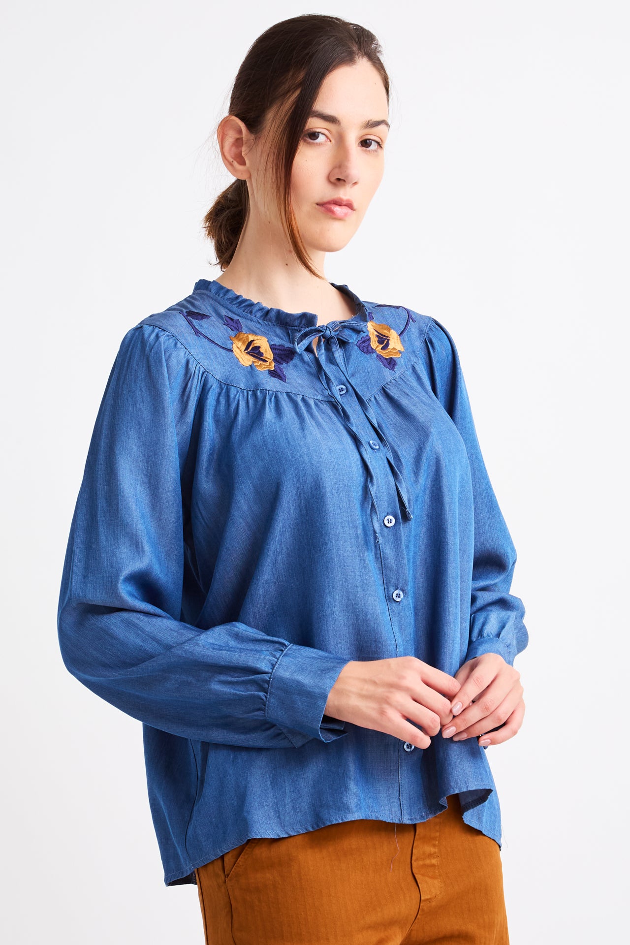 Woman wearing a blue blouse with embroidery on a white background