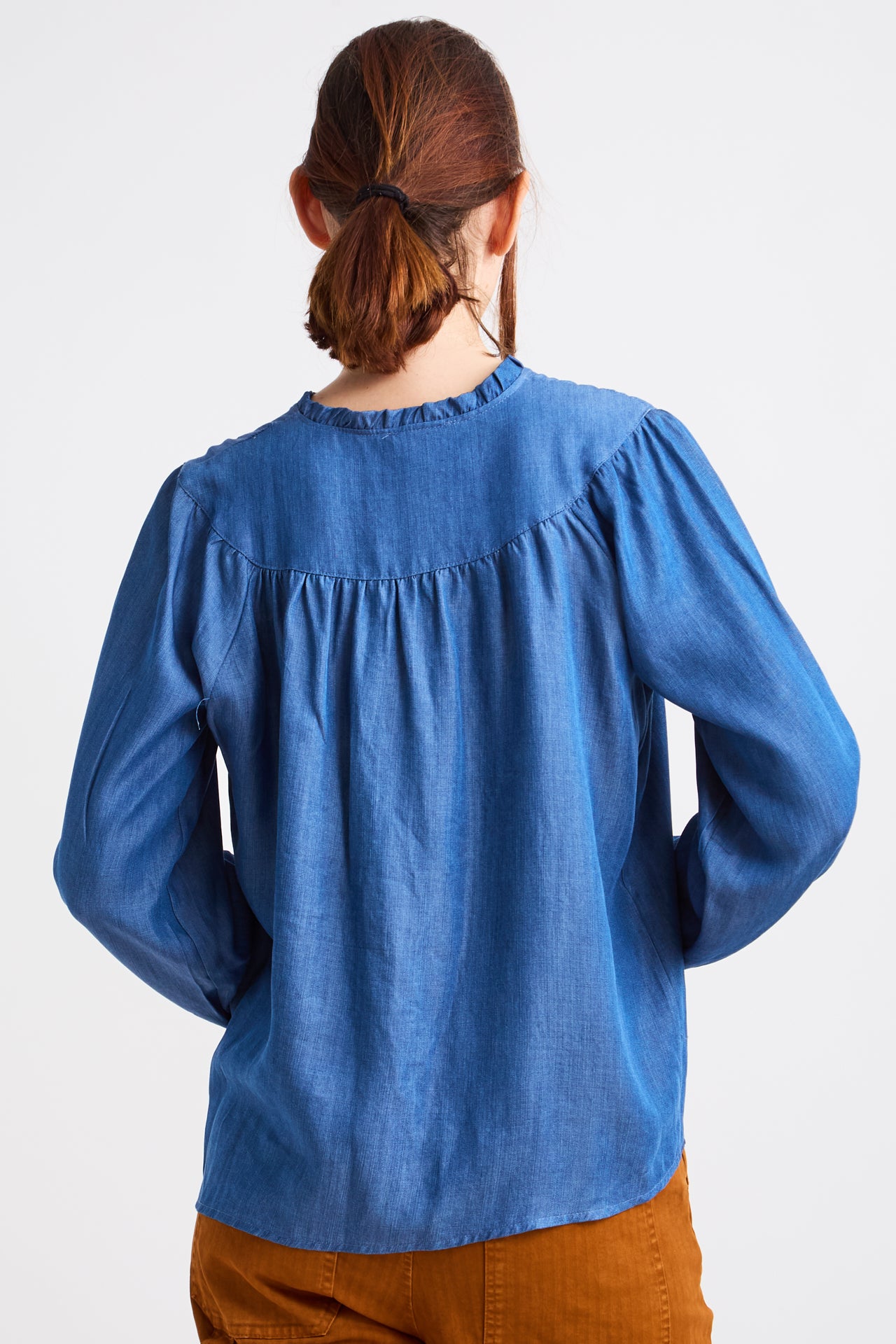 Person wearing a blue blouse with long sleeves on a white background