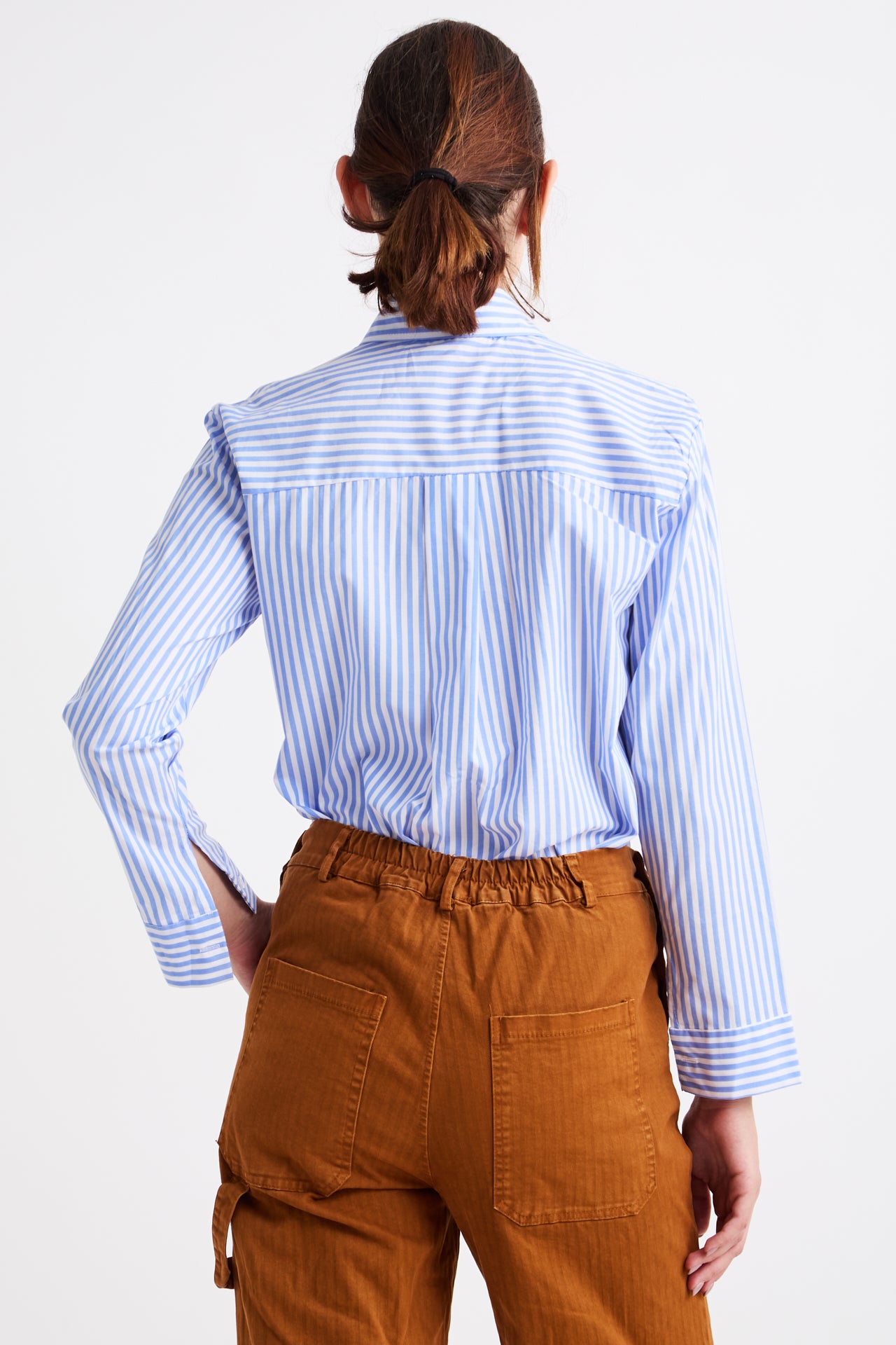 Person wearing a blue and white striped shirt and brown pants on a white background