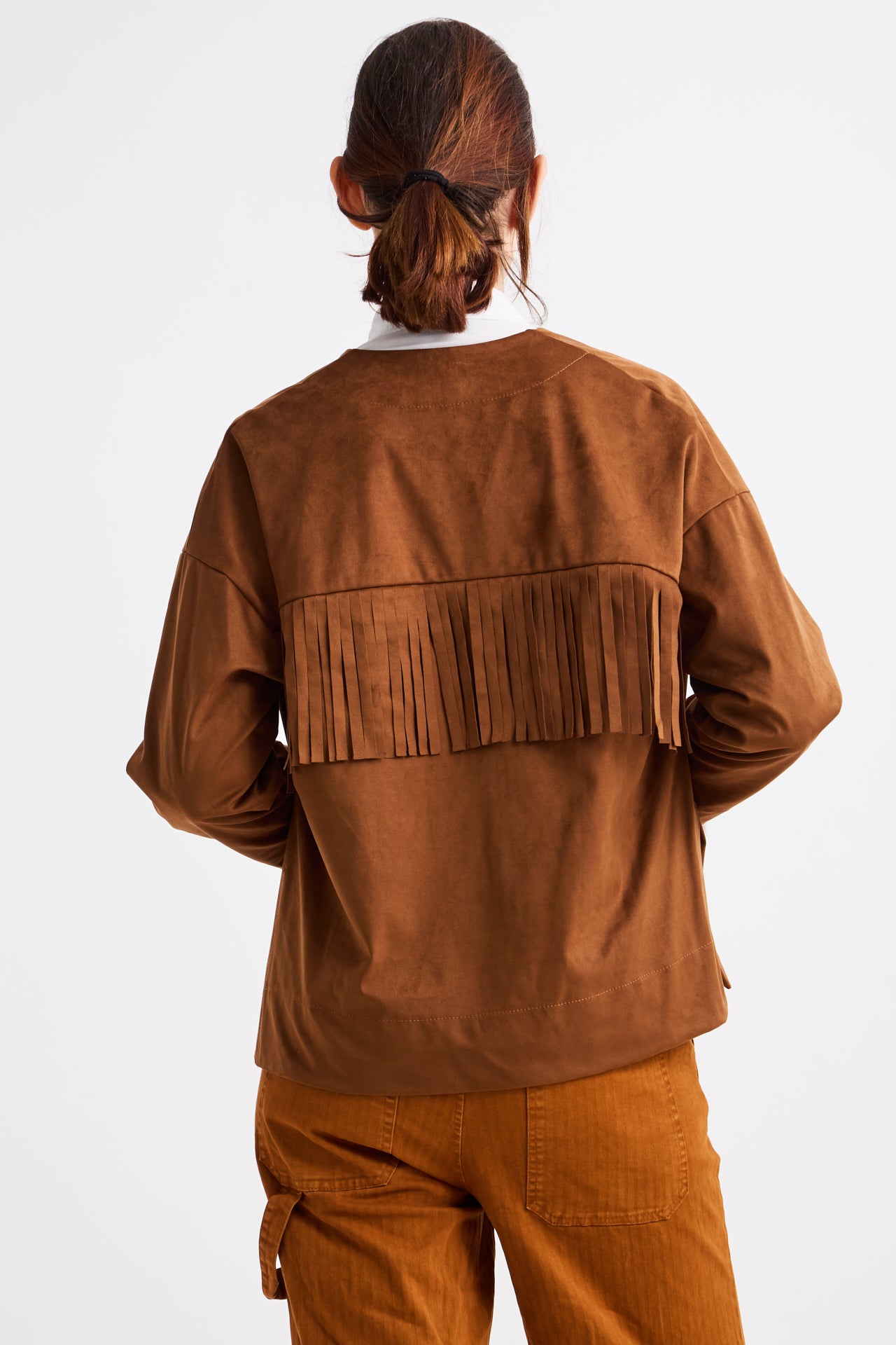 Person wearing a brown suede jacket with fringe details on a white background