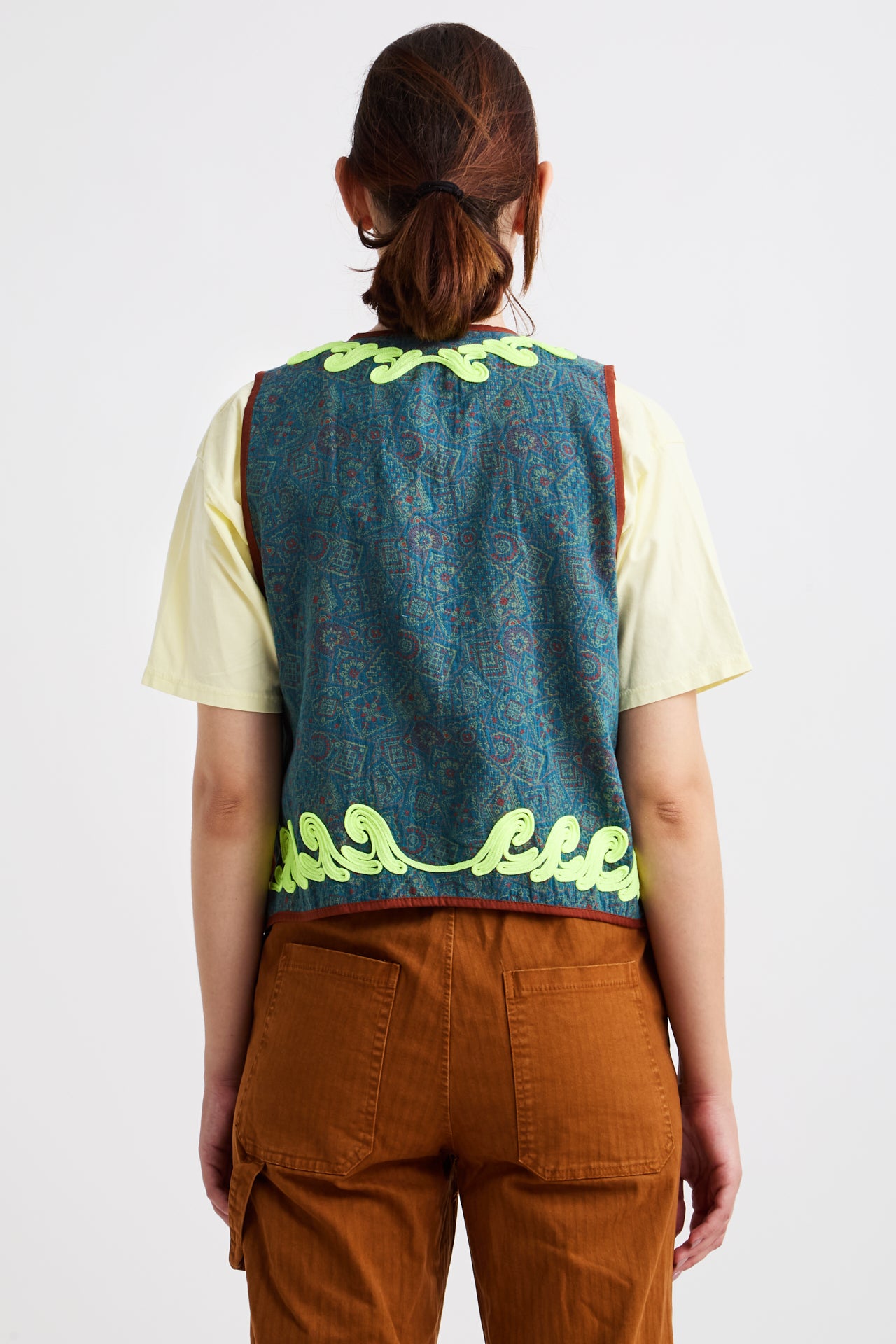 Person wearing a blue patterned vest with green accents on a white background