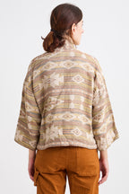 Person wearing a patterned shirt and brown pants on a white background