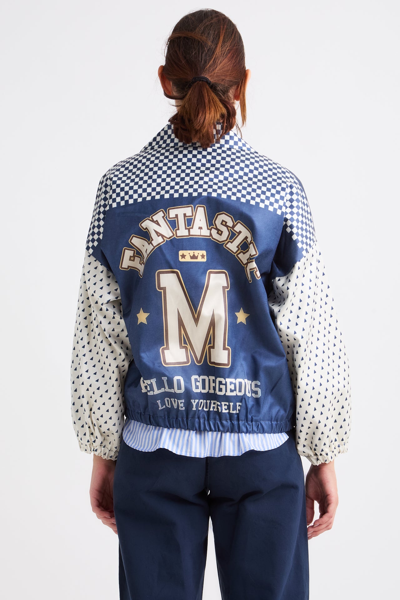 Person wearing a blue and white checkered jacket with 'Fantasy' and 'Mello Gorgeous' text on the back.
