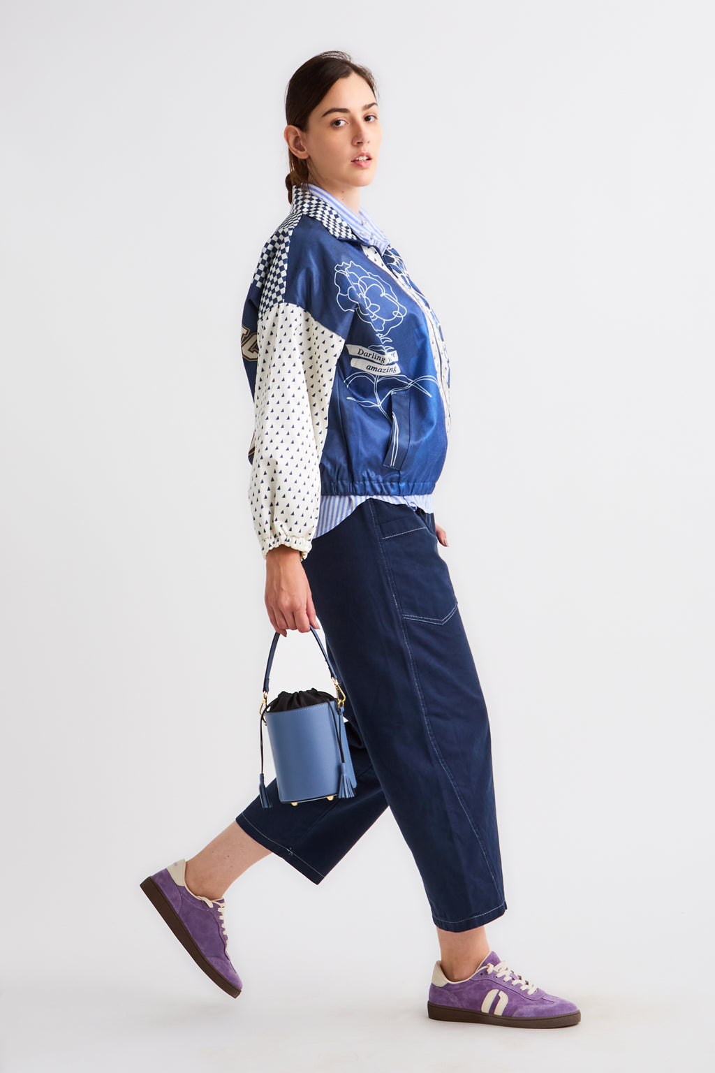 Person wearing a colorful jacket with a blue bag on a white background