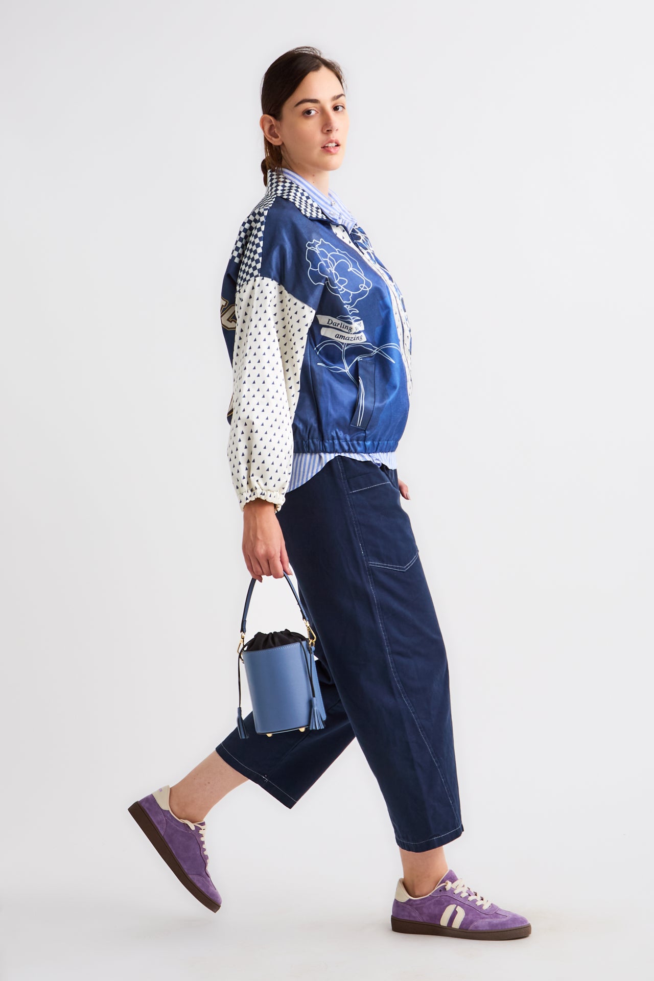 Person wearing a colorful jacket with a blue bag on a white background