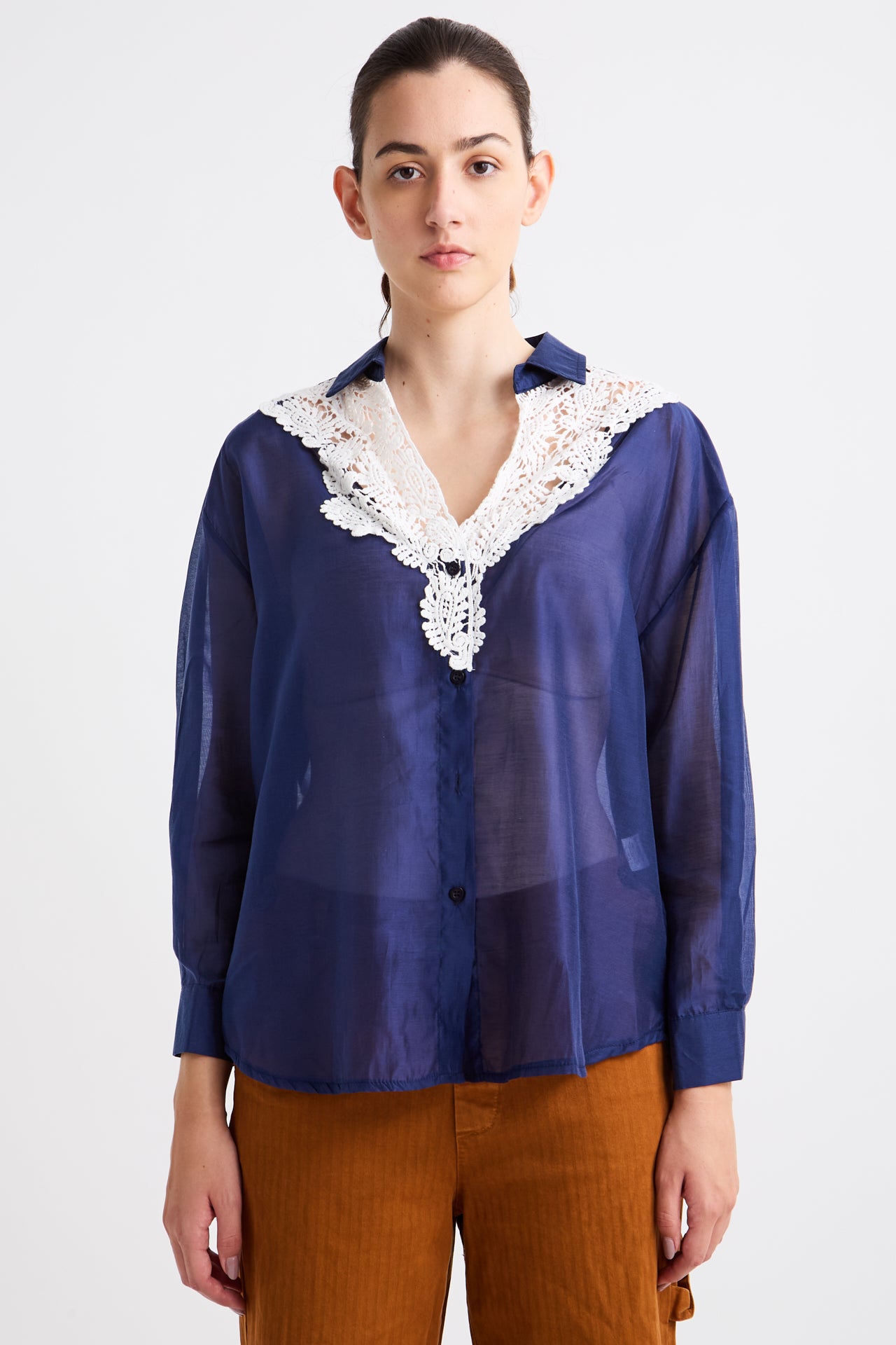Person wearing a blue blouse with lace details on a white background