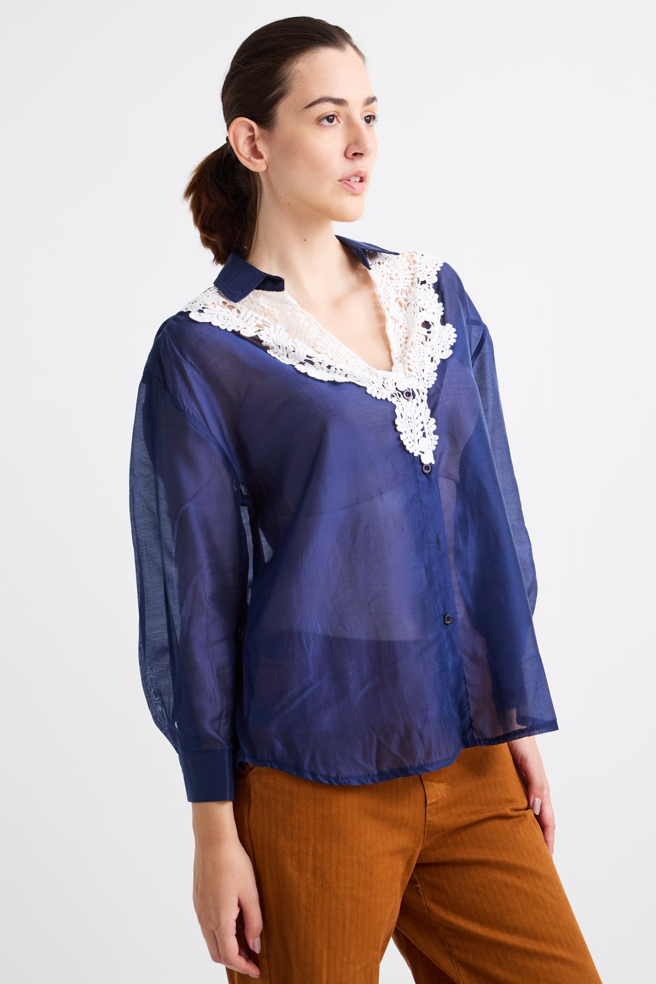 Woman wearing a blue blouse with lace details on a white background
