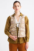 Person wearing a patterned vest over a shirt with a plain background