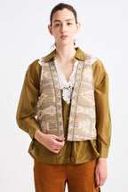 Person wearing a patterned vest over a shirt with a plain background