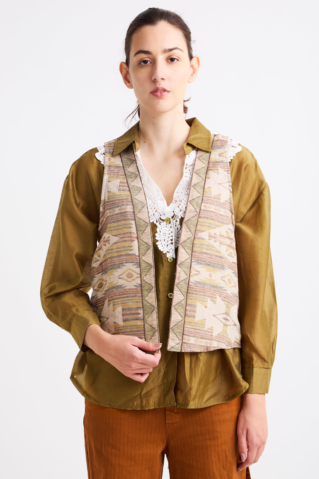 Person wearing a patterned vest over a shirt with a plain background