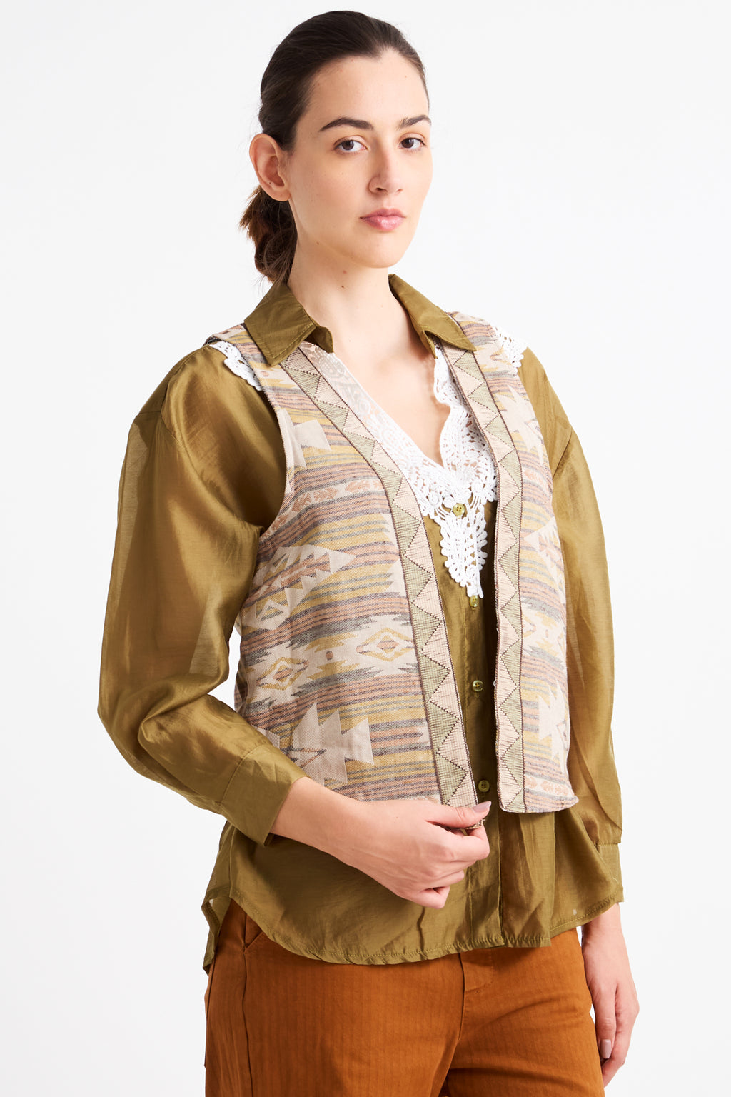 Woman wearing a green blouse with a patterned vest on a white background