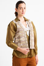 Woman wearing a green blouse with a patterned vest on a white background