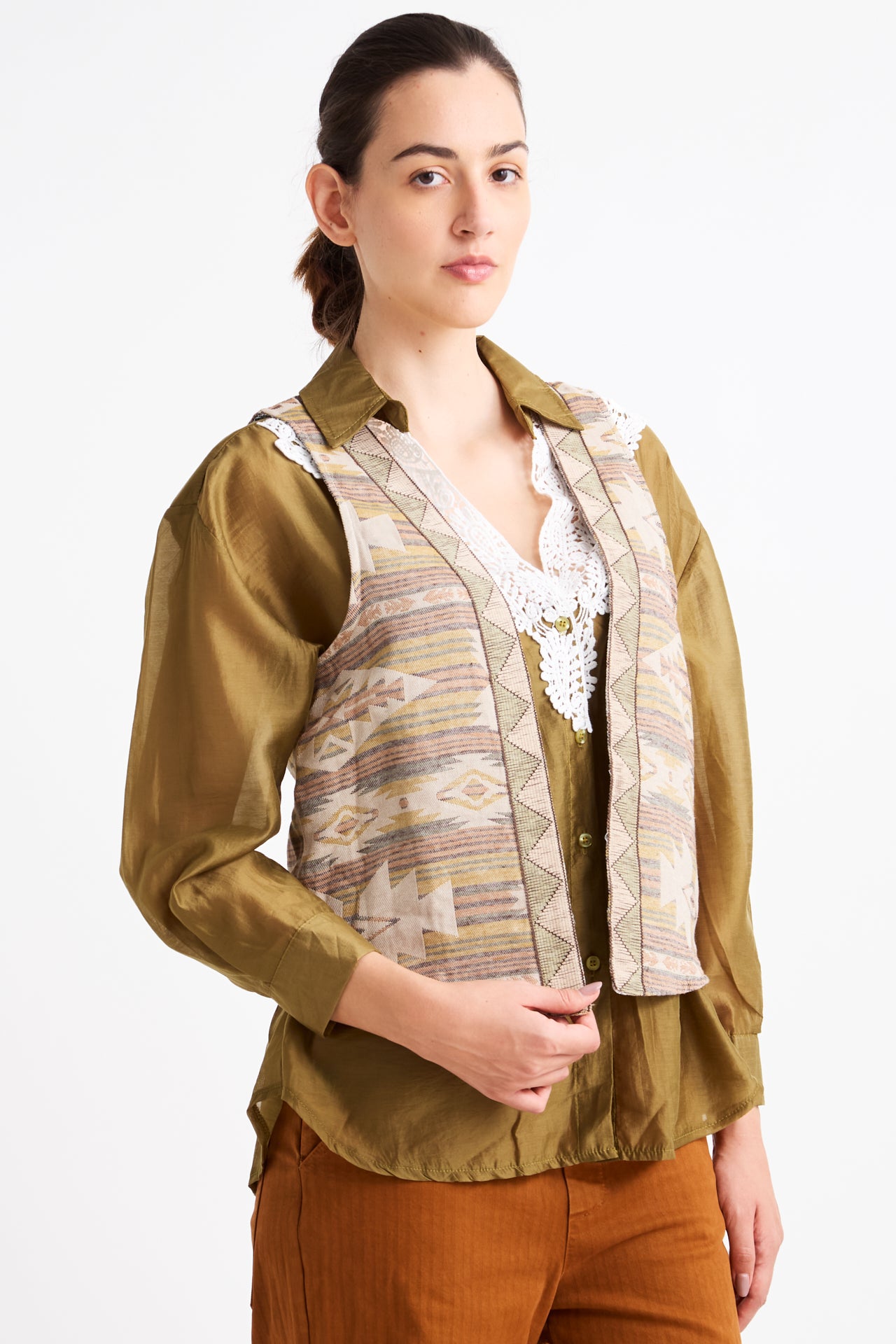 Woman wearing a green blouse with a patterned vest on a white background
