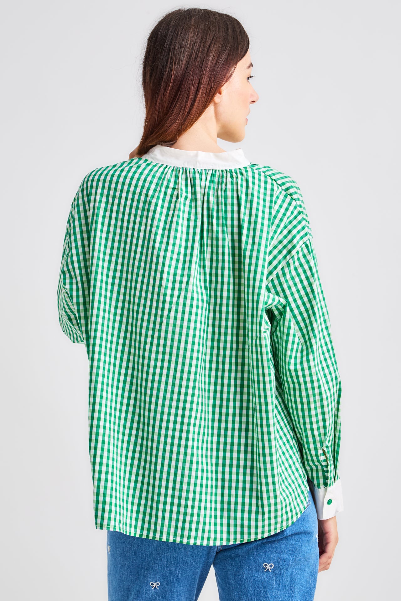 Woman wearing a green and white checkered shirt on a plain background